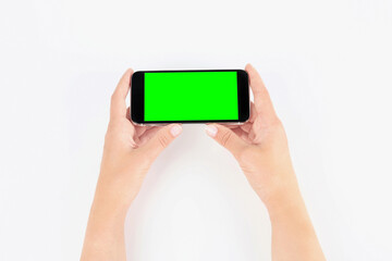 Young woman holding smartphone with green screen on white background, top view. Mockup for design