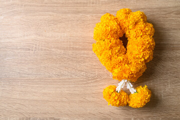 Yellow marigold flower garland on wooden background, Spiritual flower