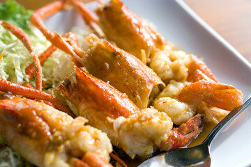 Deep fried river prawns with tamarind sauce decorated with shredded cabbage served on white plate.