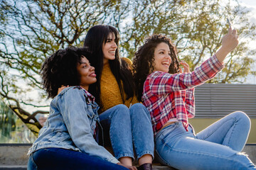 three young, multi-racial, female exchange student friends take a selfie on a staircase, smiling