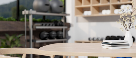 Copy space on table with books and flower vase over blurred background of fitness room