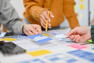 close-up, A professional female graphic designer pointing her pen on paper, discussing with her team.