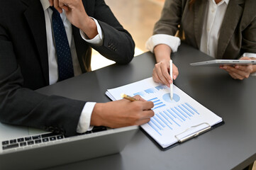 Professional Asian businessman working with a female accountant, pen pointing on paper. top view