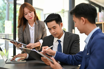 Professional Asian male boss working with his financial analysts, reviewing financial report