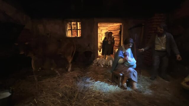 Unusual modern representation for Christmas decorations with hand-painted nativity figurines. In this scene mother father and child with cow and sheep in a moment of family life. Zoom in