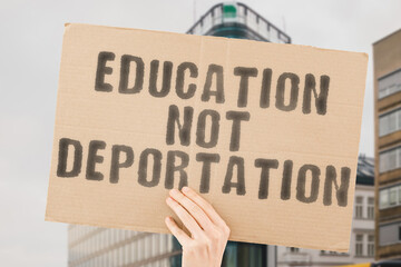 The phrase " Education Not Deportation " is on a banner in men's hands with blurred background. Mass. School. Security. Student. Weapon. Defense. Pistol. Shoot. War. Gun. Dirty. Fear. Horror. Military