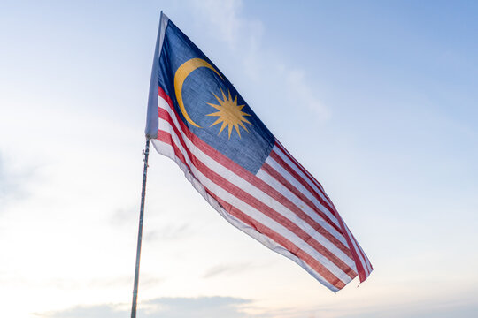 Malaysia flag also known as Jalur Gemilang against bright blue sunrise sky. Malaysia Independence Day.