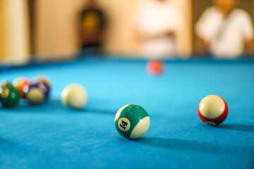 Colorful billiard balls on a blue billiard table. Billiard ball with number fourteen.