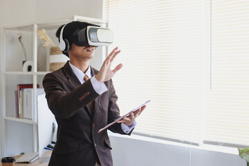 Businessman in suit using virtual reality glasses and headset is gesturing hands as if touching at...