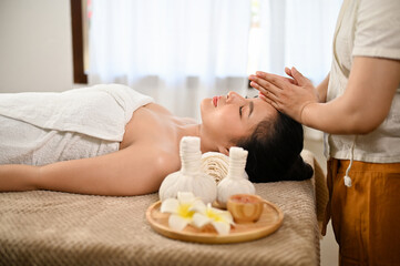 Obraz na płótnie Canvas side view, Calm Asian woman lying on massage table, getting massage. Thai spa, Thai massage