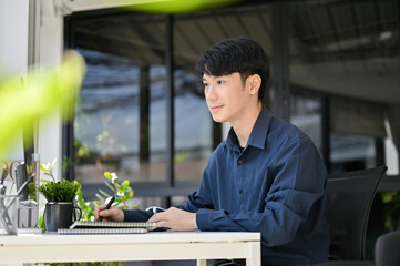 Asian Attractive businessman working on his project while sitting in a modern office room