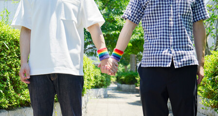 屋外で虹色のリストバンドをして散歩する男性カップル　顔無し