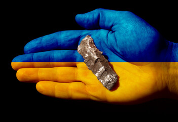 A fragment of an artillery shell in the palm of your hand on a black background.