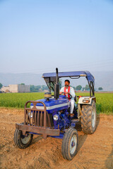 Fototapeta premium Indian farmer sitting on tractor at agriculture field.