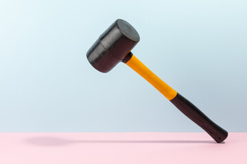 Orange and black rubber hammer isolated on a cyan and pink background