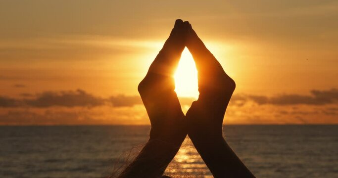 Woman hand close up at golden sunset, sun flare human hand inside, peace and meditation simbol, love, relax and healthy life concept, Silhouette of girl hand at sunset, sea ocean beach scene