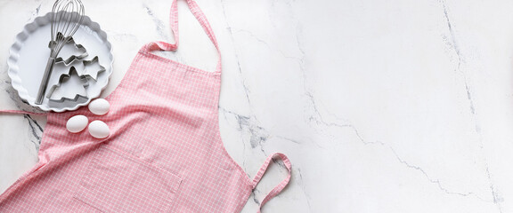 Clean apron, kitchen utensils and eggs on white background with space for text