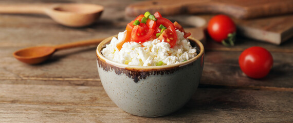 Bowl with fresh cottage cheese, tomatoes and green onion on wooden background