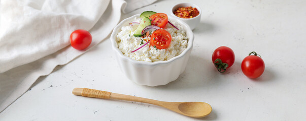 Bowl with fresh cottage cheese and vegetables on light background