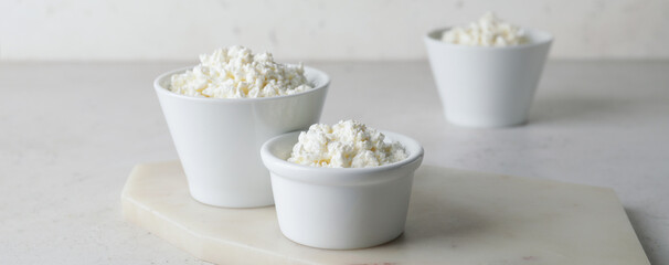 Bowls with fresh cottage cheese on light background