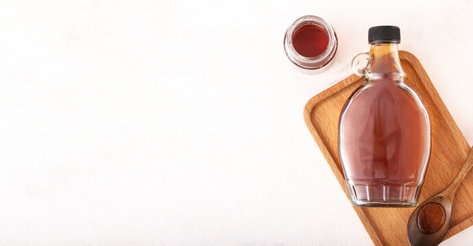 Tasty maple syrup on light background with space for text, top view