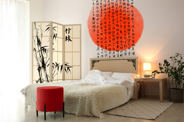 Stylish interior of light bedroom with beautiful Asian print on wall