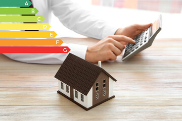House model and man with calculator at table. Concept of energy efficiency