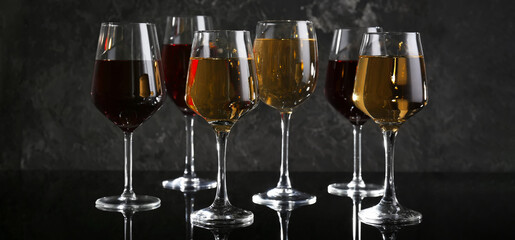 Glasses of different tasty wine on dark background