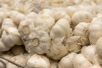 Garlic in plastic nylon mesh produce bags for sale at the supermarket.