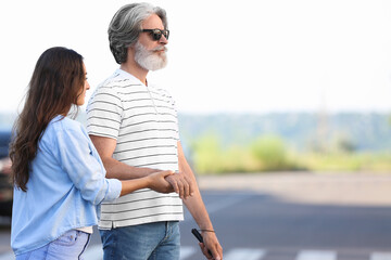 Young woman helping senior blind man to cross road in city