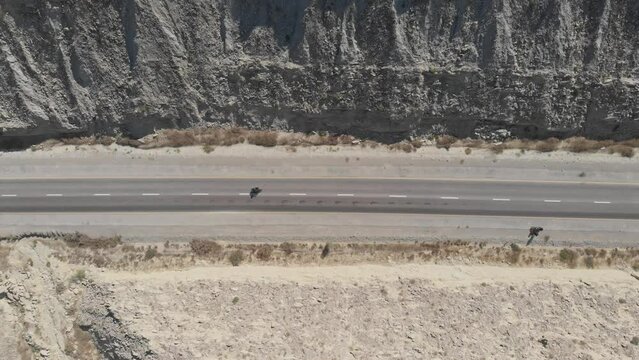 Aerial Birds Eye View Of Motorbike Driving Along Makran Coastal Highway Road Beside Dramatic Rock Formations In Hingol National Park. Dolly Right