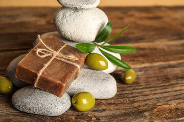 Fototapeta na wymiar Soap bar with olives and stones on table, closeup