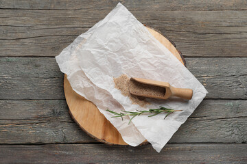 Board with baking paper, scoop of breadcrumbs and rosemary on wooden background
