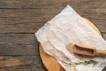 Board with baking paper, scoop of breadcrumbs and rosemary on wooden background