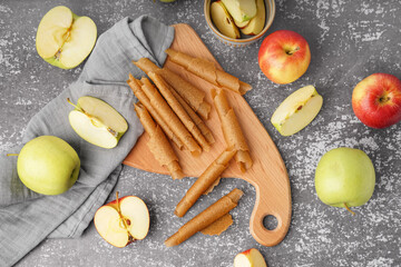 Wooden board with tasty fruit pastilles and fresh apples on grunge background