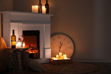 Interior of dark living room with fireplace, burning candles and wine