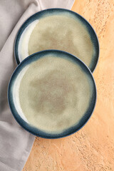 Stylish plates with grey napkin on beige grunge background