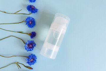 Transparent bottle of intimate lubricant gel and knapweed cornflower flowers line border on blue...