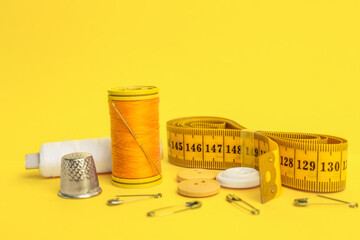 Set of sewing supplies with thread spools on yellow background