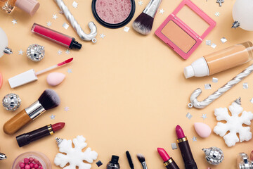 Frame made of different cosmetics, makeup accessories and Christmas decorations on color background