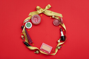 Frame made of cosmetics, ribbon and Christmas balls on red background