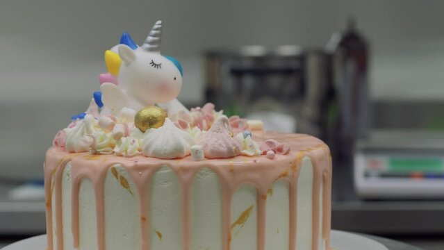 chocolate frosted pink over white drip cake with unicorn and meringue topping ready for birthday celebration 4k video