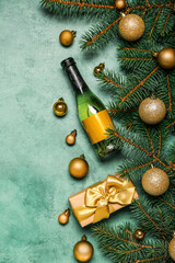 Bottle of wine with Christmas balls, fir branches and gift on green background