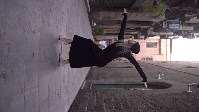 vertical woman young caucasian blonde female dancer black dress dancing in narrowed street of Barcelona Downtown spain