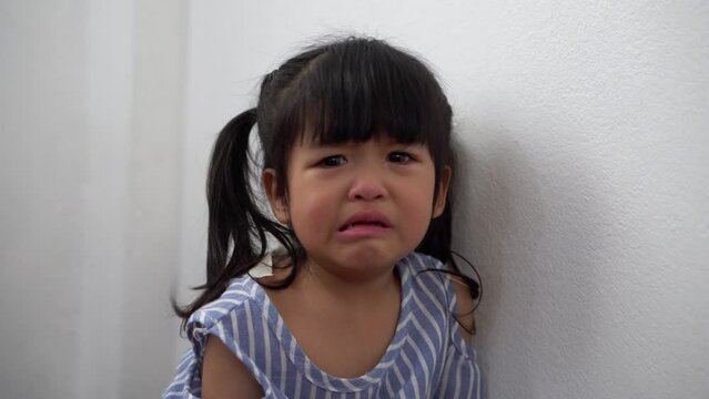 A Litter Asian girl sitting in room conner and crying after Punished by the blackout.