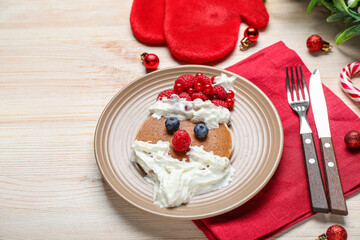 Plate with tasty Santa Claus pancake and Christmas decorations on wooden background