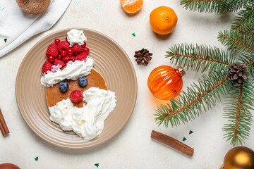 Plate with tasty Santa pancake and Christmas decorations on light background