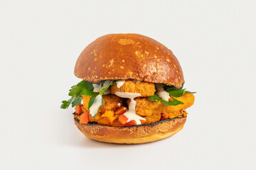 Burger made from chicken schnitzel, tahini sauce, fresh buns and parsley on white background.