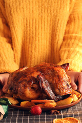 Woman with plate of Christmas chicken with potato on dining table at home, closeup