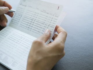 Fototapeta premium Hand Holding Book Bank on Wooden Background,Checking Pay and Dep Statement on Passbook,Balance Financial Paycheck Document Income,Plan Investment Cash Money and saving Business,Accounting currency.